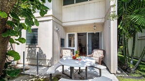 Eine Terrasse mit einem runden Tisch, zwei Stühlen und einem kleinen Gartenbereich.