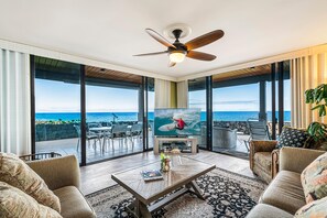 Ein geräumiges Wohnzimmer mit großem Fernseher, bequemen Sitzgelegenheiten und Blick auf den Ozean.
