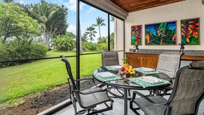 A dining area with a view of a lush garden, a wooden ceiling, and three colorful paintings on the wall. - Keauhou Kona Surf & Racquet Club #6-104 (Kailua-Kona)