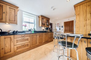 A kitchen with wooden cabinets, a black countertop, and two bar stools.
