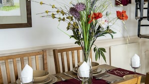 Mesa posta com pratos, talheres e um vaso de flores.