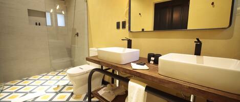 Un baño con ducha, dos lavamanos, un espejo y piso estampado.