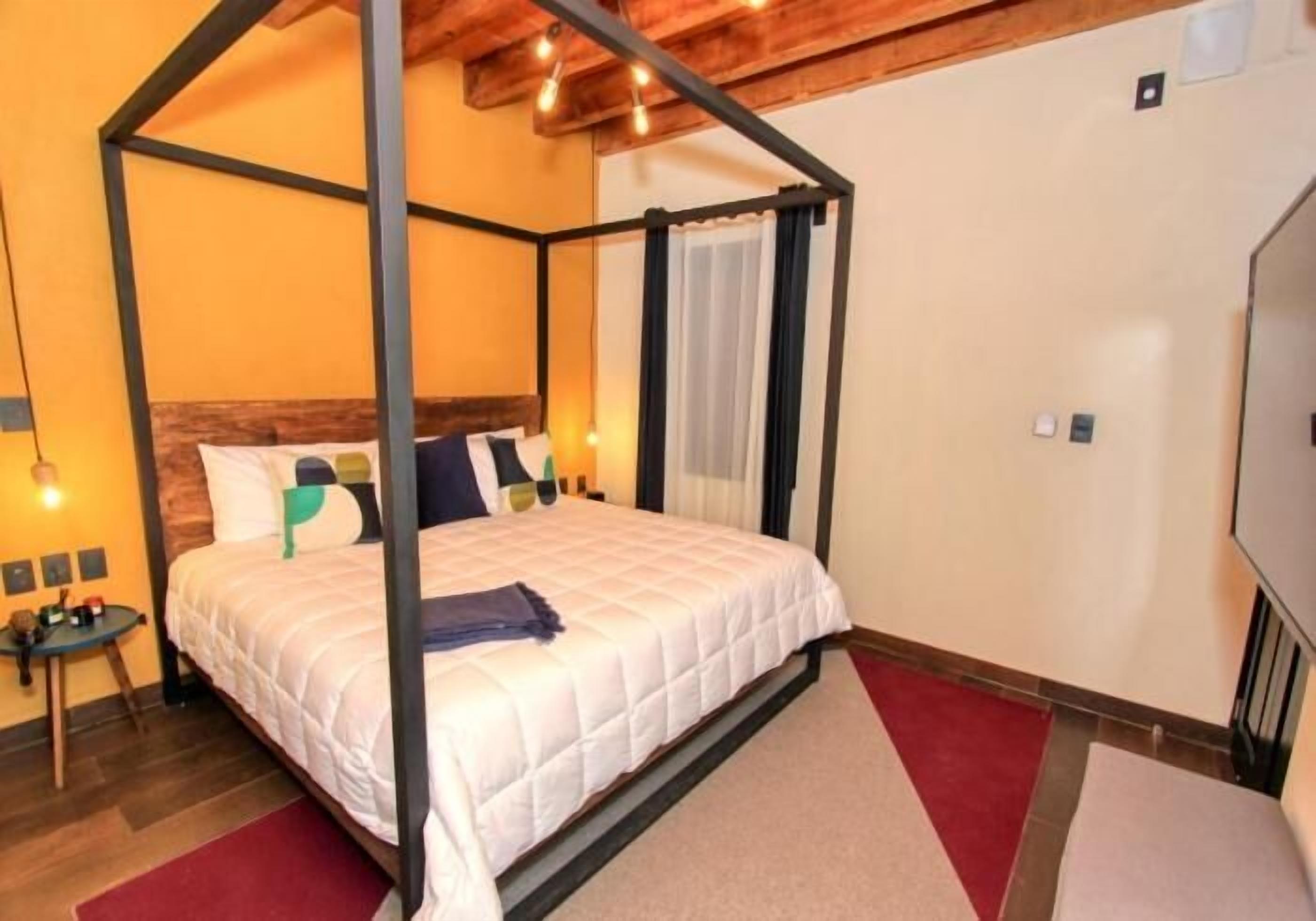 Una cama con dosel con colcha blanca, cabecera de madera y alfombra roja.