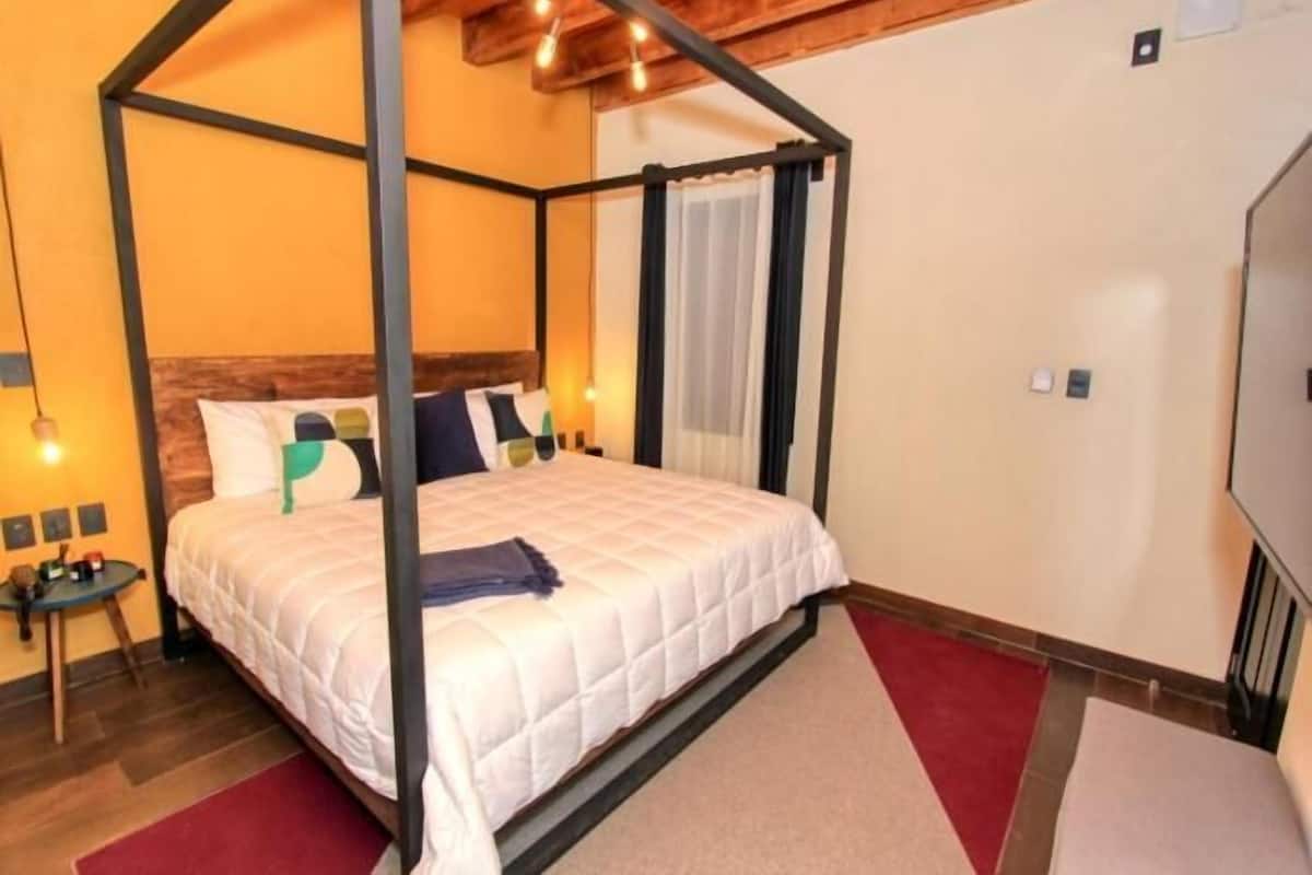 Una cama con dosel con colcha blanca, cabecera de madera y alfombra roja.