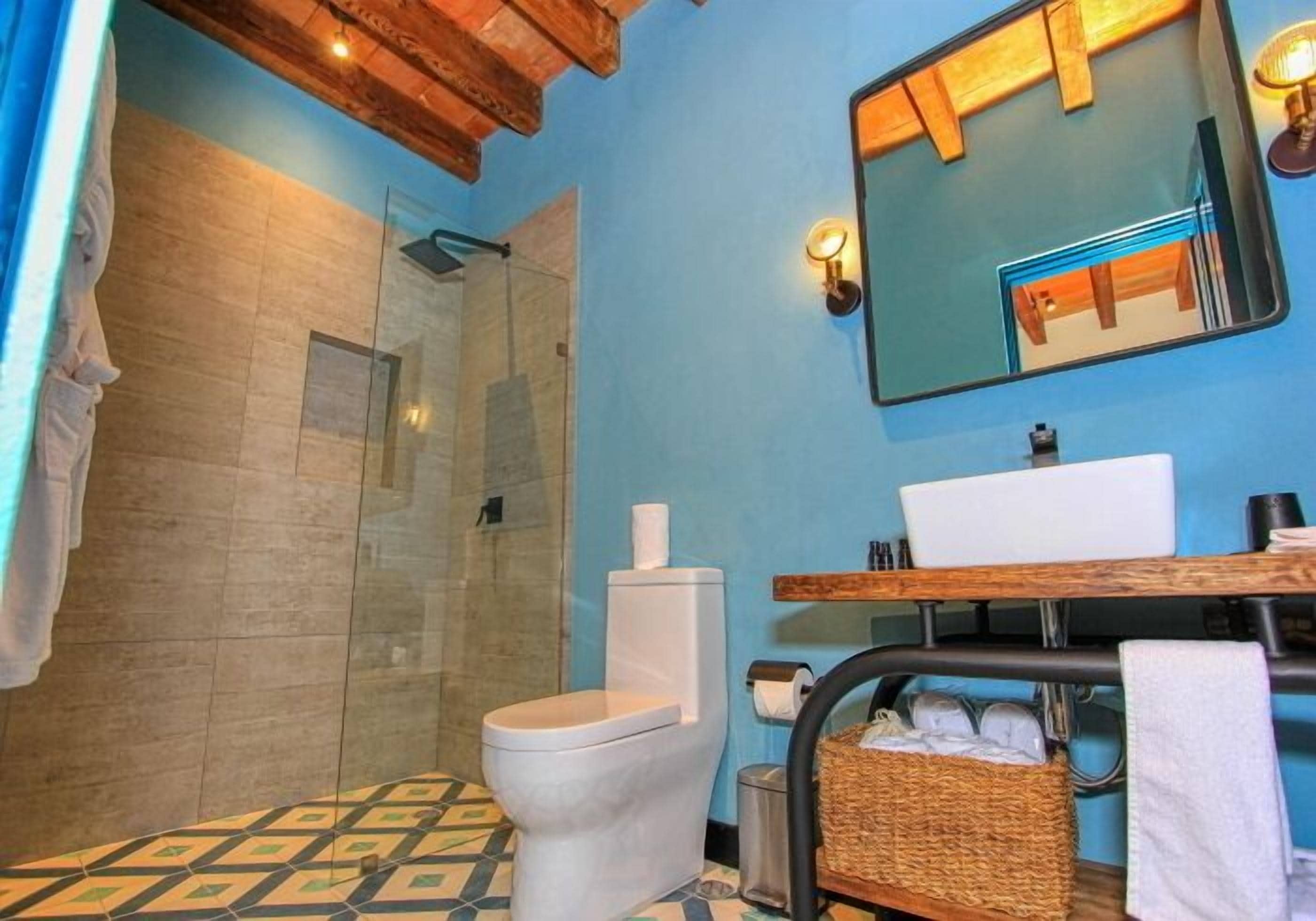 A bathroom with a shower, toilet, sink, and a mirror.
