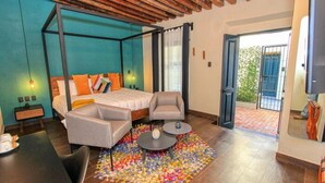 Un dormitorio moderno con cama con dosel, una zona de estar con una mesita y una alfombra colorida.