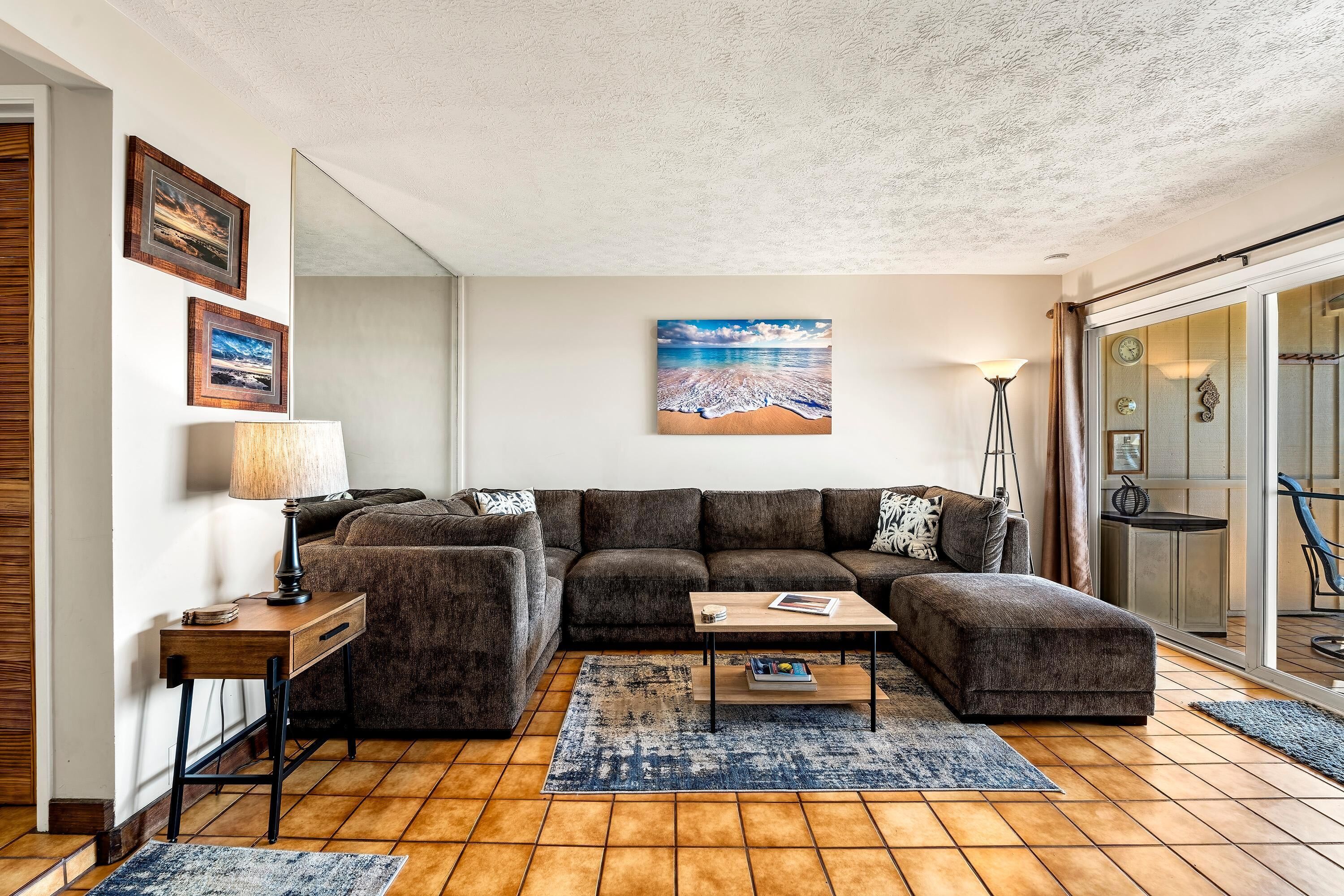 En moderne stue med en modulsofa, et sofabord og et stort maleri af en strand.