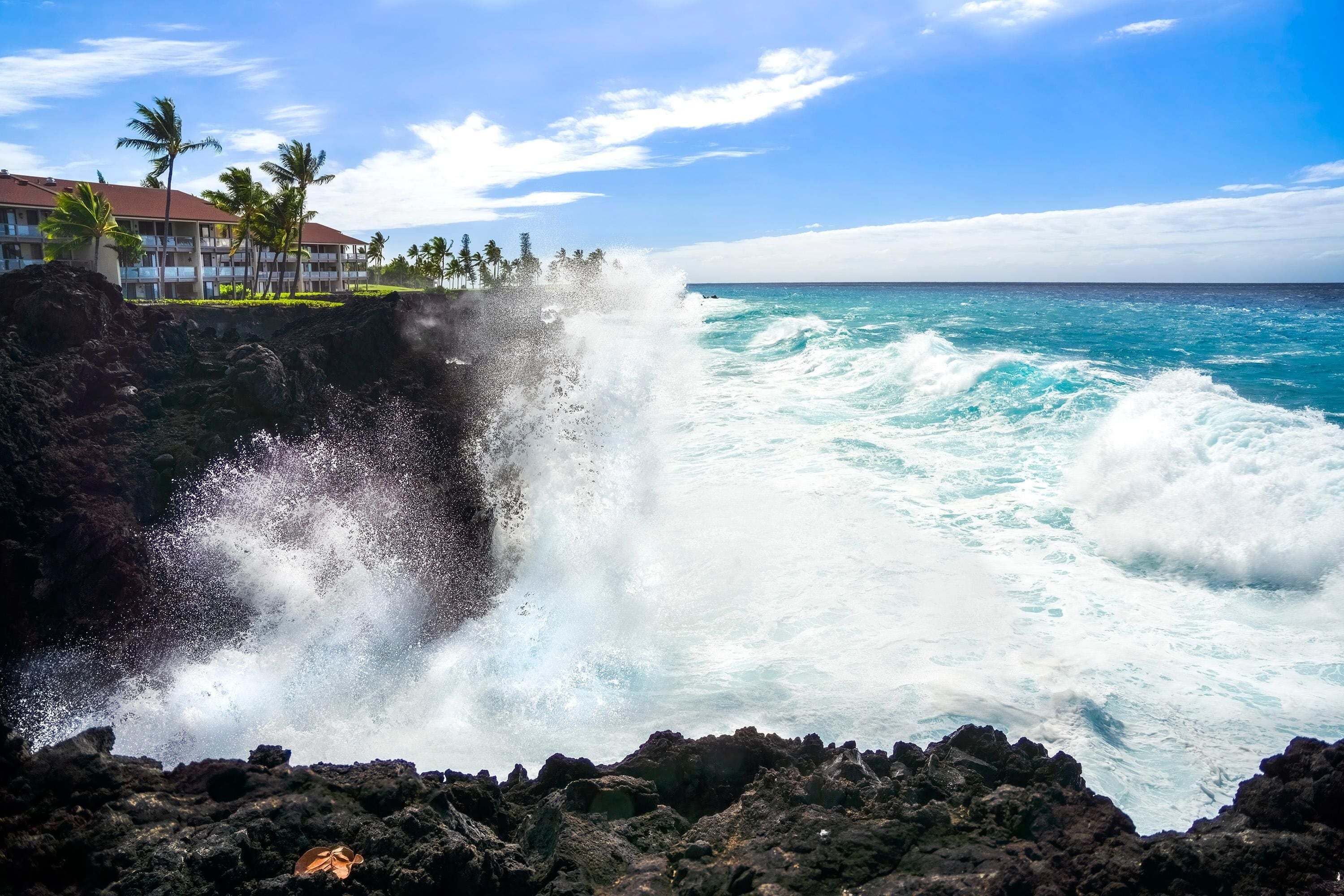 A coastal hotel with a view of the ocean and a waterfall crashing into the sea.