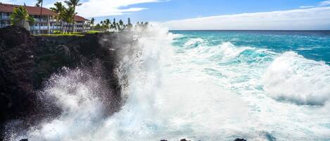 A coastal hotel with a view of the ocean and a waterfall crashing into the sea.