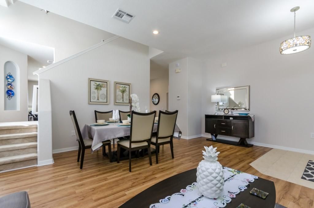 A dining area with a table set for four, a dark wooden cabinet, and a staircase leading to another level.