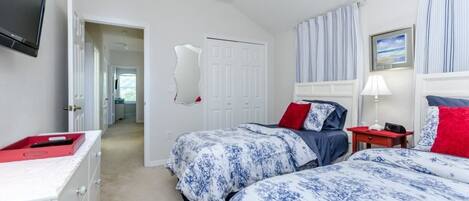 Un dormitorio con dos camas, televisión, puerta y ventana con cortinas.