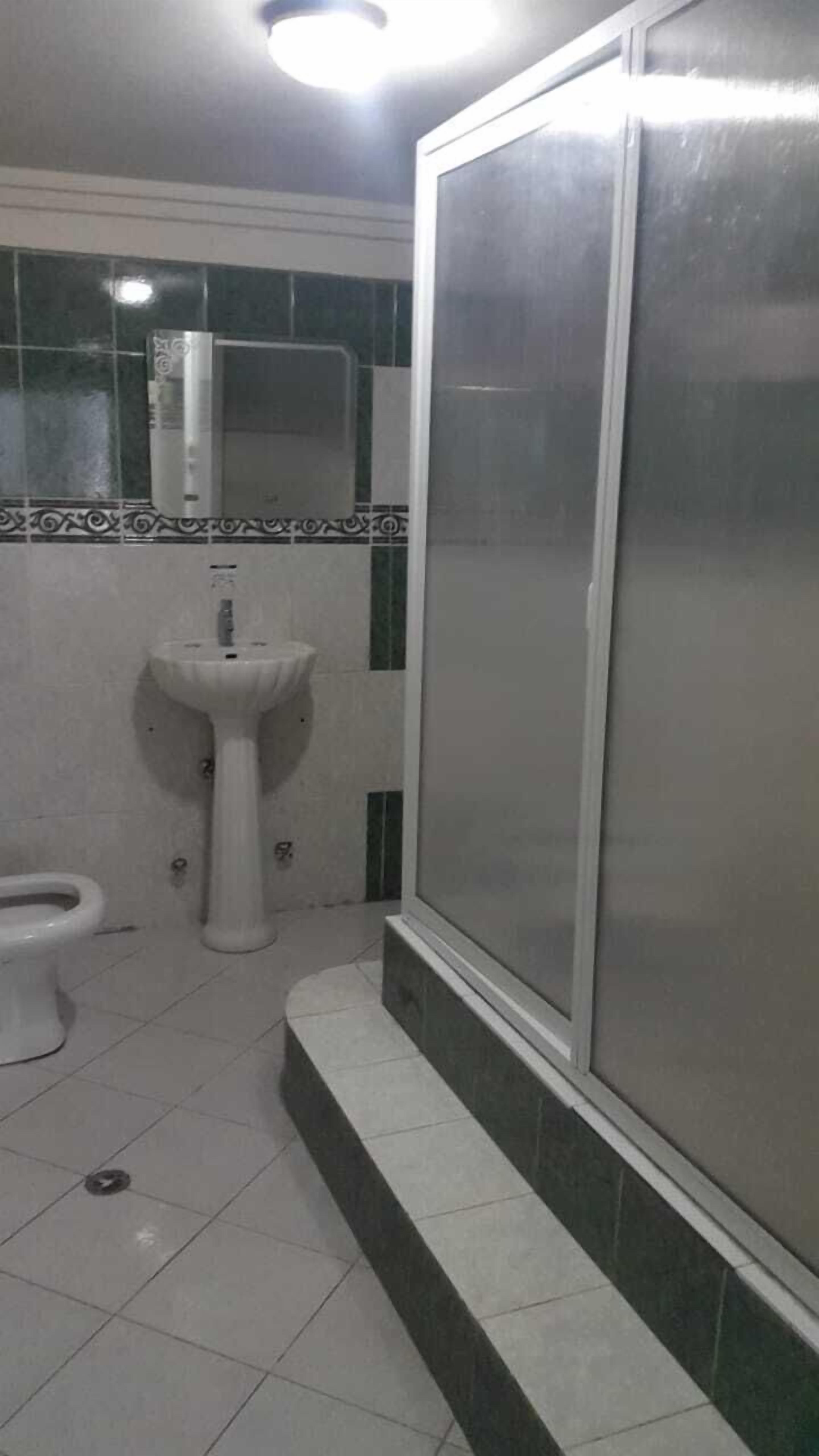 Un baño con inodoro, lavamanos pedestal y cabina de ducha.