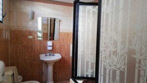 A bathroom with a toilet, pedestal sink, and a mirror. - Unihotel (Loja)