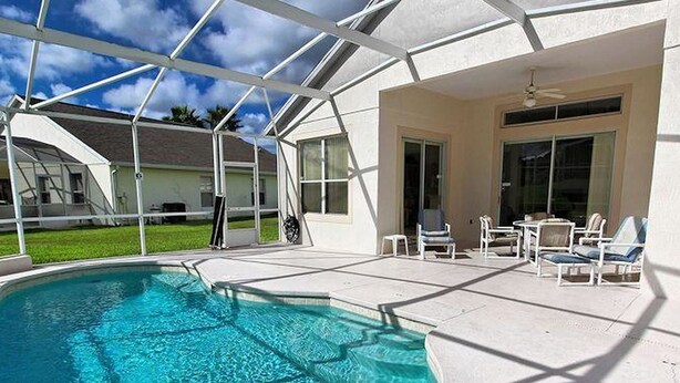 Une piscine extérieure couverte, avec une eau d’un bleu limpide, entourée d’une terrasse blanche et de chaises longues.