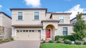 A two-story house with a red door, beige exterior, and a garage.
