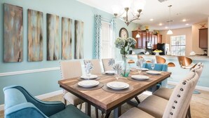 A dining area with a wooden table set for six, surrounded by upholstered chairs. - Spetacular Champios Gate 5 Bedroom (Davenport)