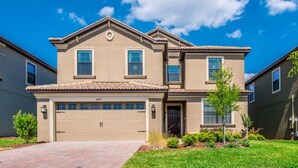 A two-story house with a beige exterior, a tiled roof, and a garage. - 6 Bedroom 5 Bathroom Vacation Home (Davenport)