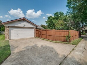 A residential garage with a wooden fence and a clear driveway.