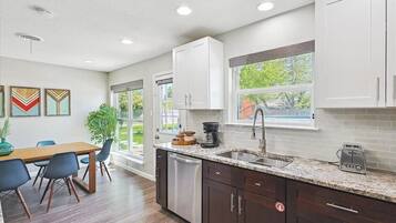 A modern kitchen with white cabinets, a granite countertop, and a dishwasher.