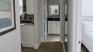 Een gang met een keukenhoek, een badkamer en een slaapkamer.