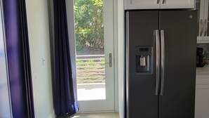 Een moderne keuken met een inbouwkoelkast, witte kastjes en een schuifdeur naar een buitenruimte.