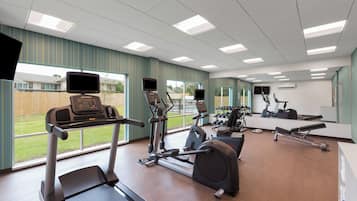 Un gimnasio con cintas de correr, elípticas y equipo de pesas.