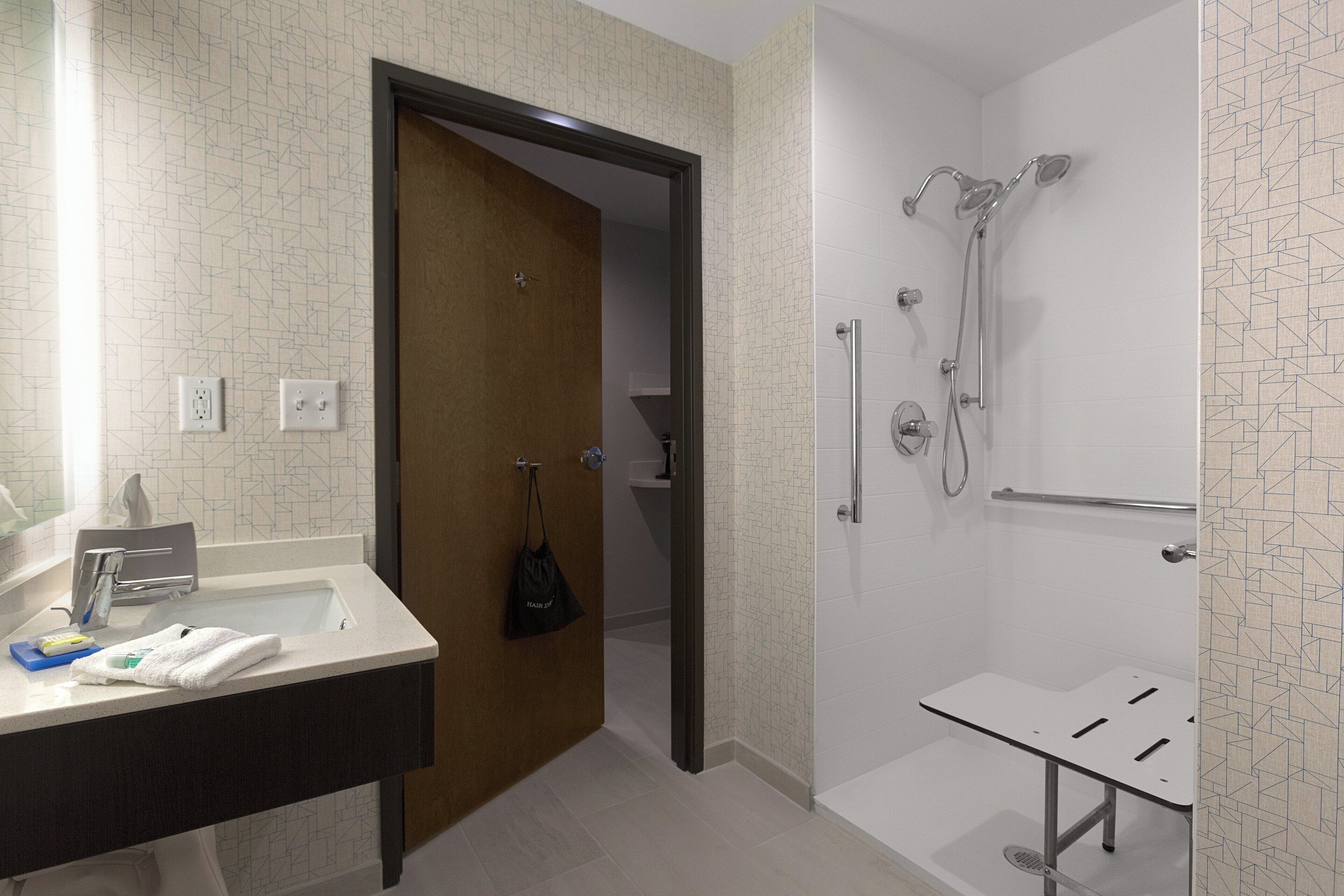 A bathroom with a shower, a sink, and a towel rack.
