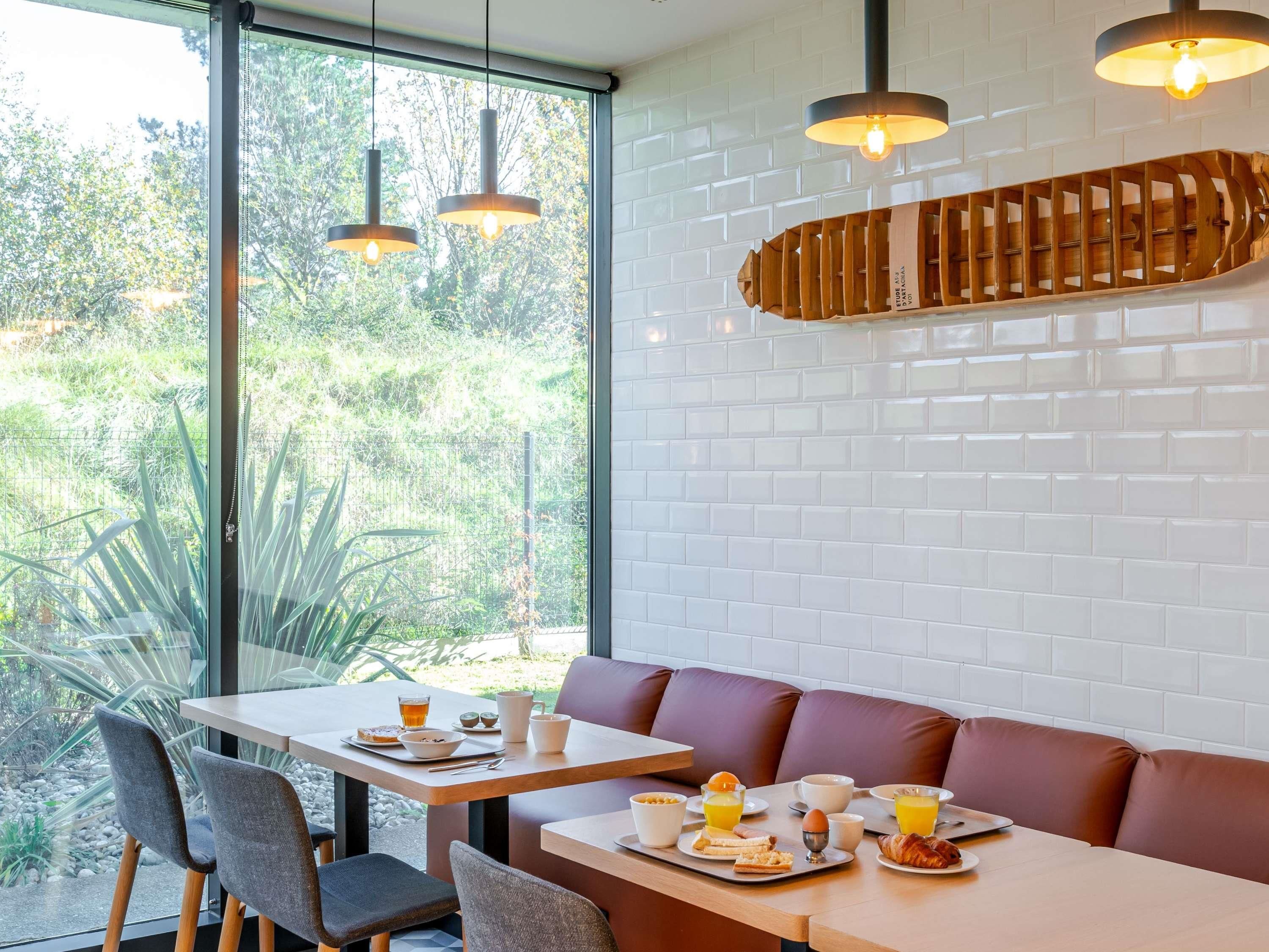 A dining area with a table set for breakfast, including plates of food, cups, and a beverage.