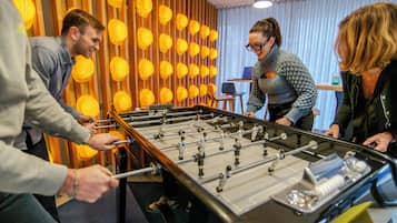 A foosball table in a room with wooden slats and yellow spherical decorations on the wall.