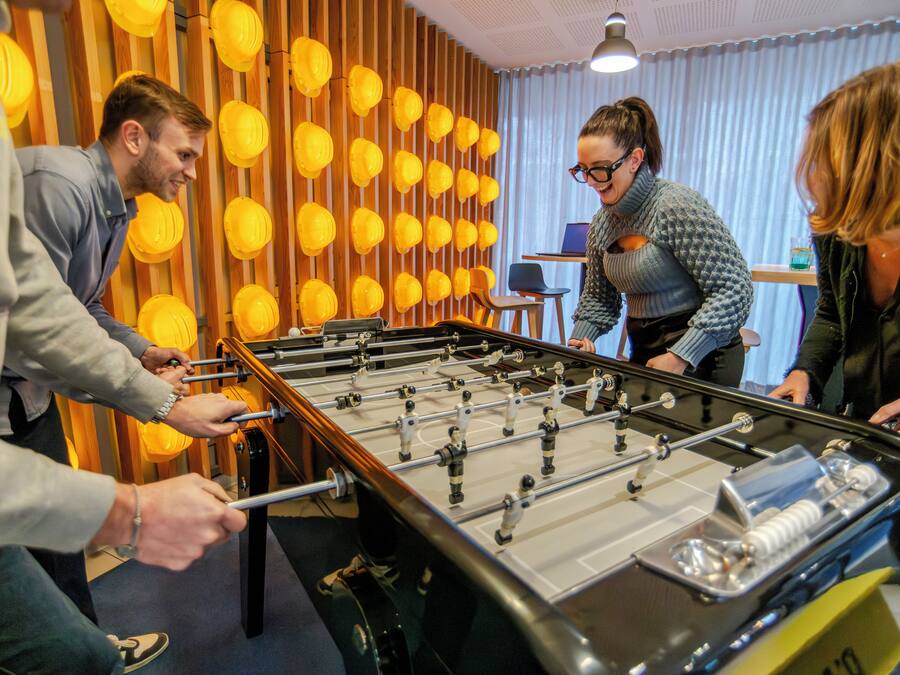 A foosball table in a room with wooden slats and yellow spherical decorations on the wall.
