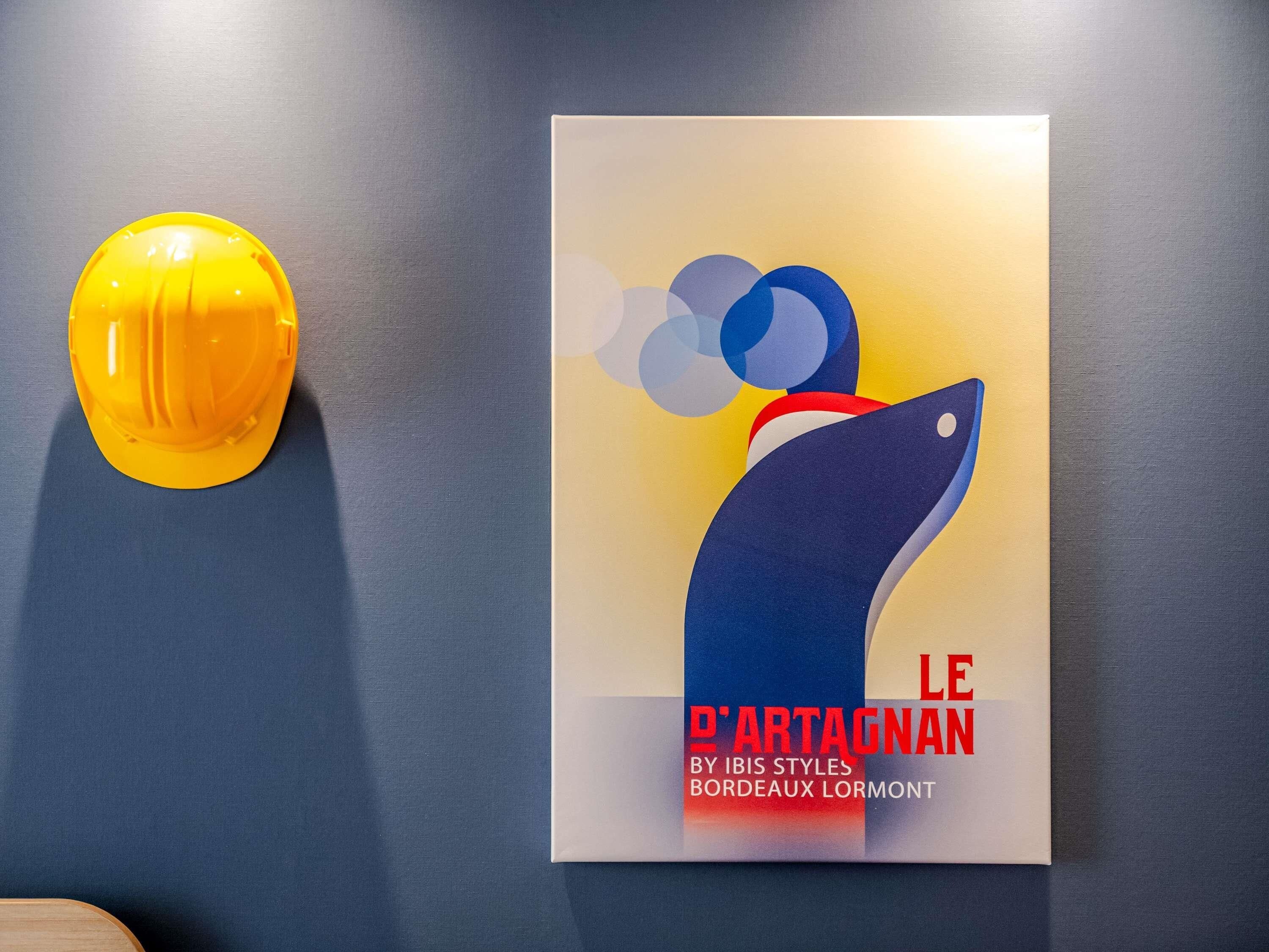 Un mur orné d’un casque de chantier jaune et d’une affiche représentant un poisson bleu avec du texte.