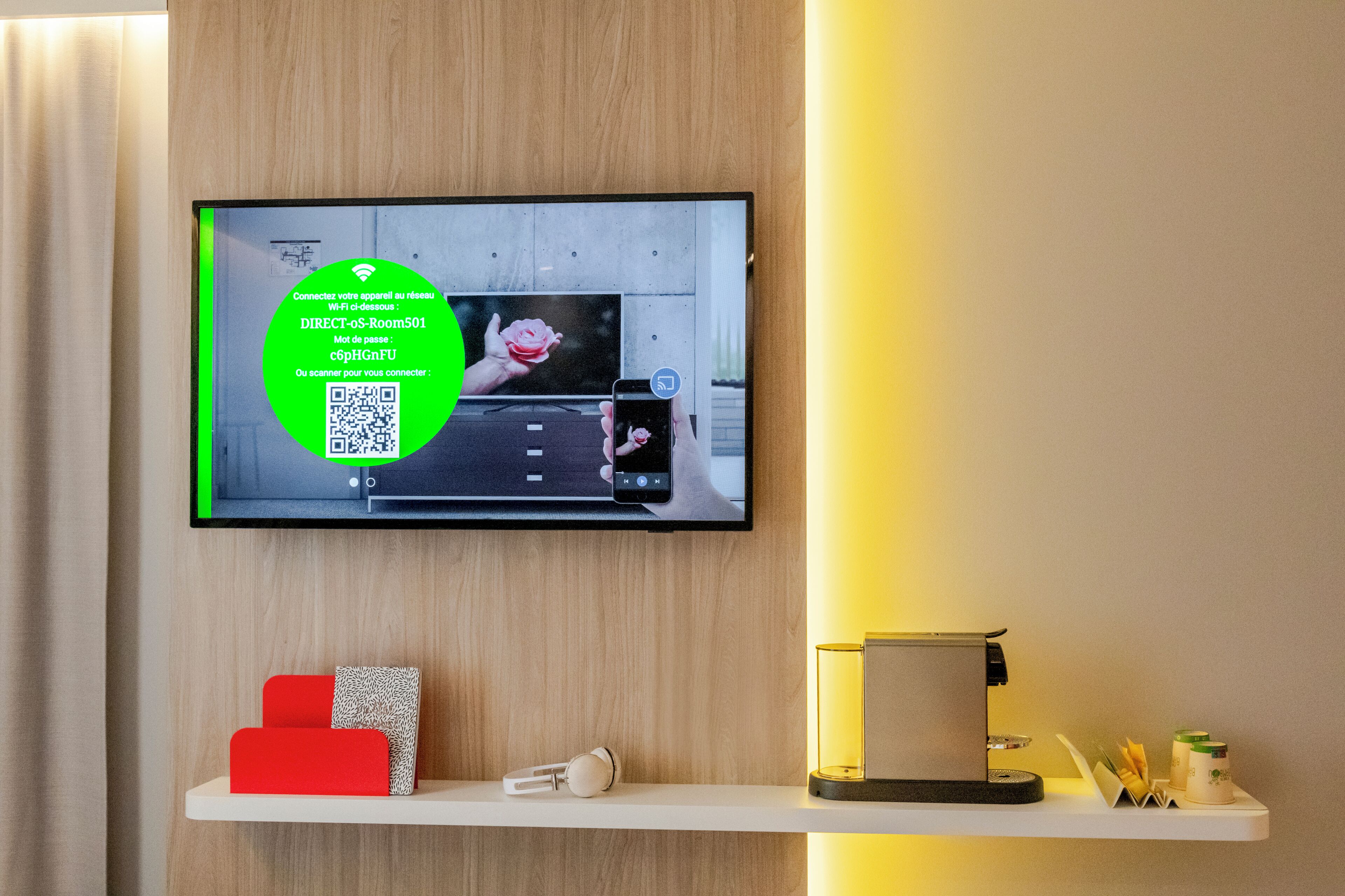 A television mounted on a wall displaying a QR code and Wi-Fi details.