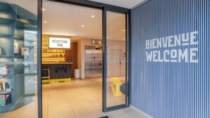 L’entrée d’un hôtel avec un comptoir d’accueil, un panneau d’accueil et un bureau d’enregistrement.