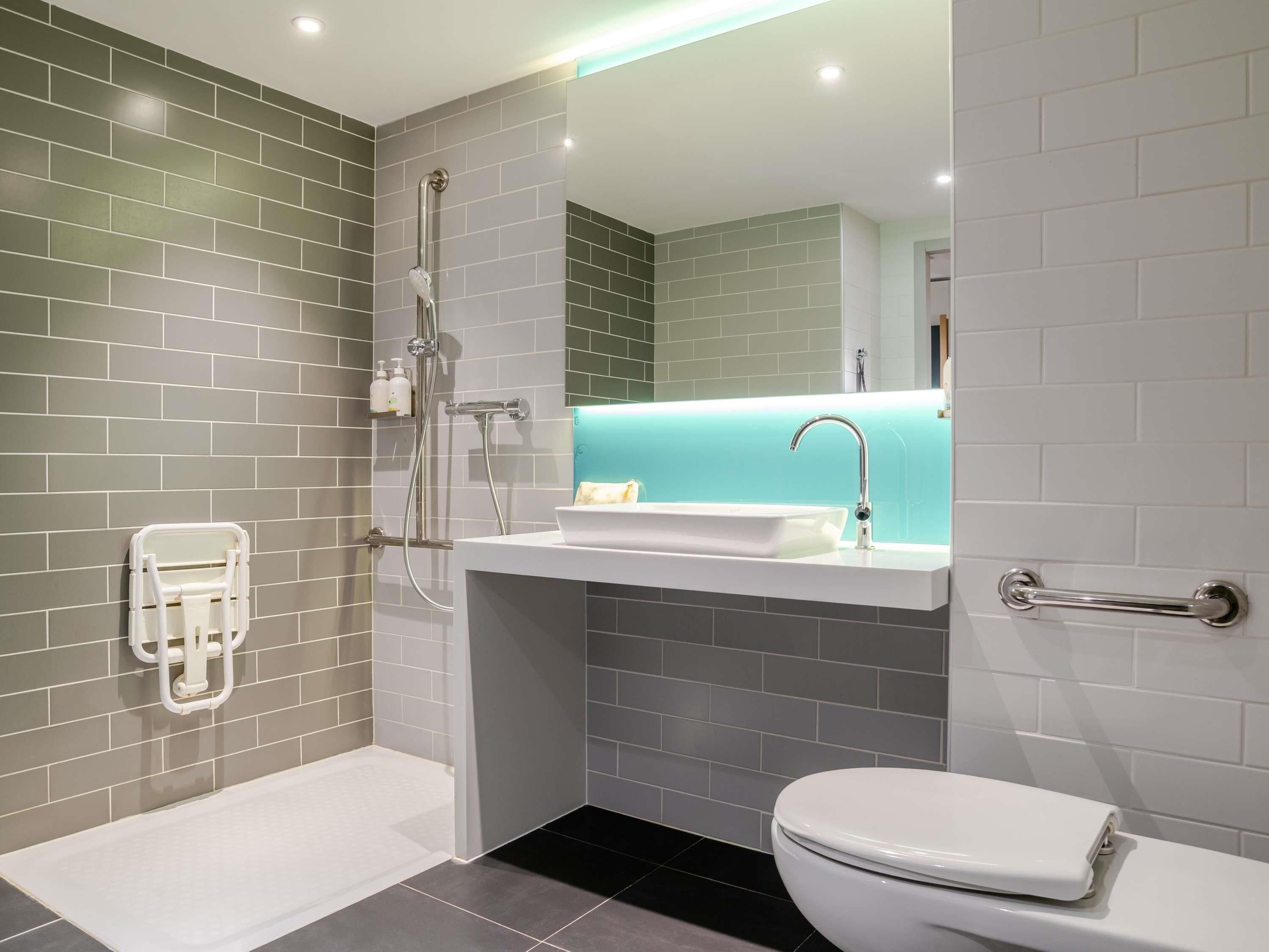 Een moderne badkamer met een douche, wastafel en toilet.