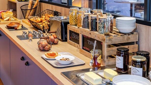 Un buffet de petit-déjeuner proposant une variété d’aliments, notamment du pain, des céréales et des condiments.