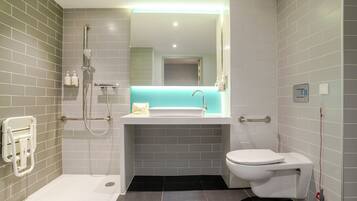 A modern bathroom with a walk-in shower, a white sink, and a toilet.