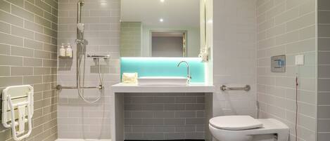 A modern bathroom with a walk-in shower, a white sink, and a toilet.