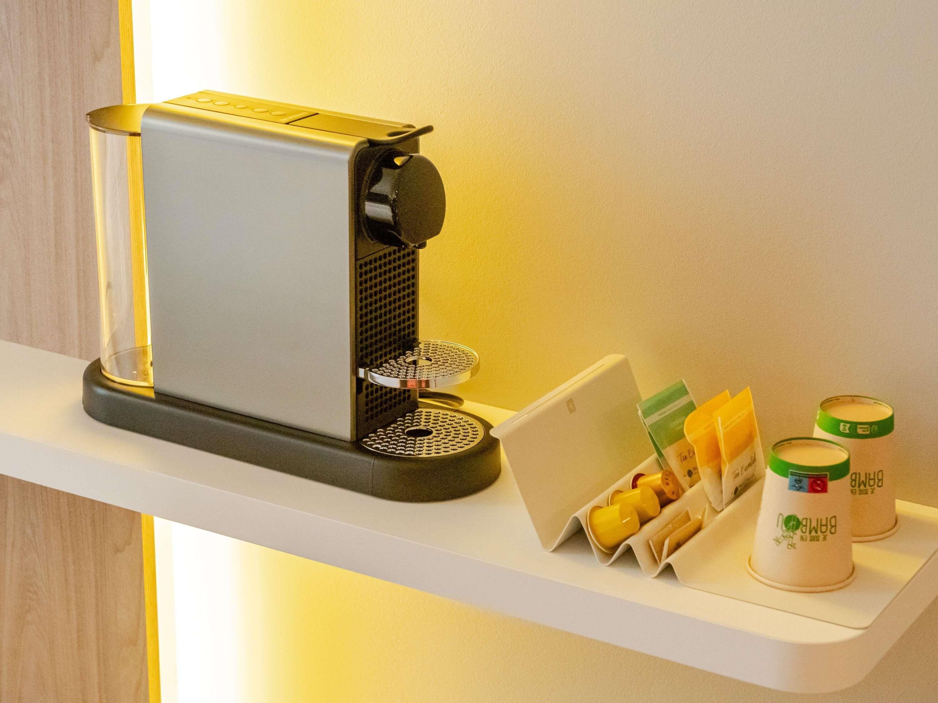 Een koffieapparaat op een wit schap, met een kaart houder en twee koffiecontainers.