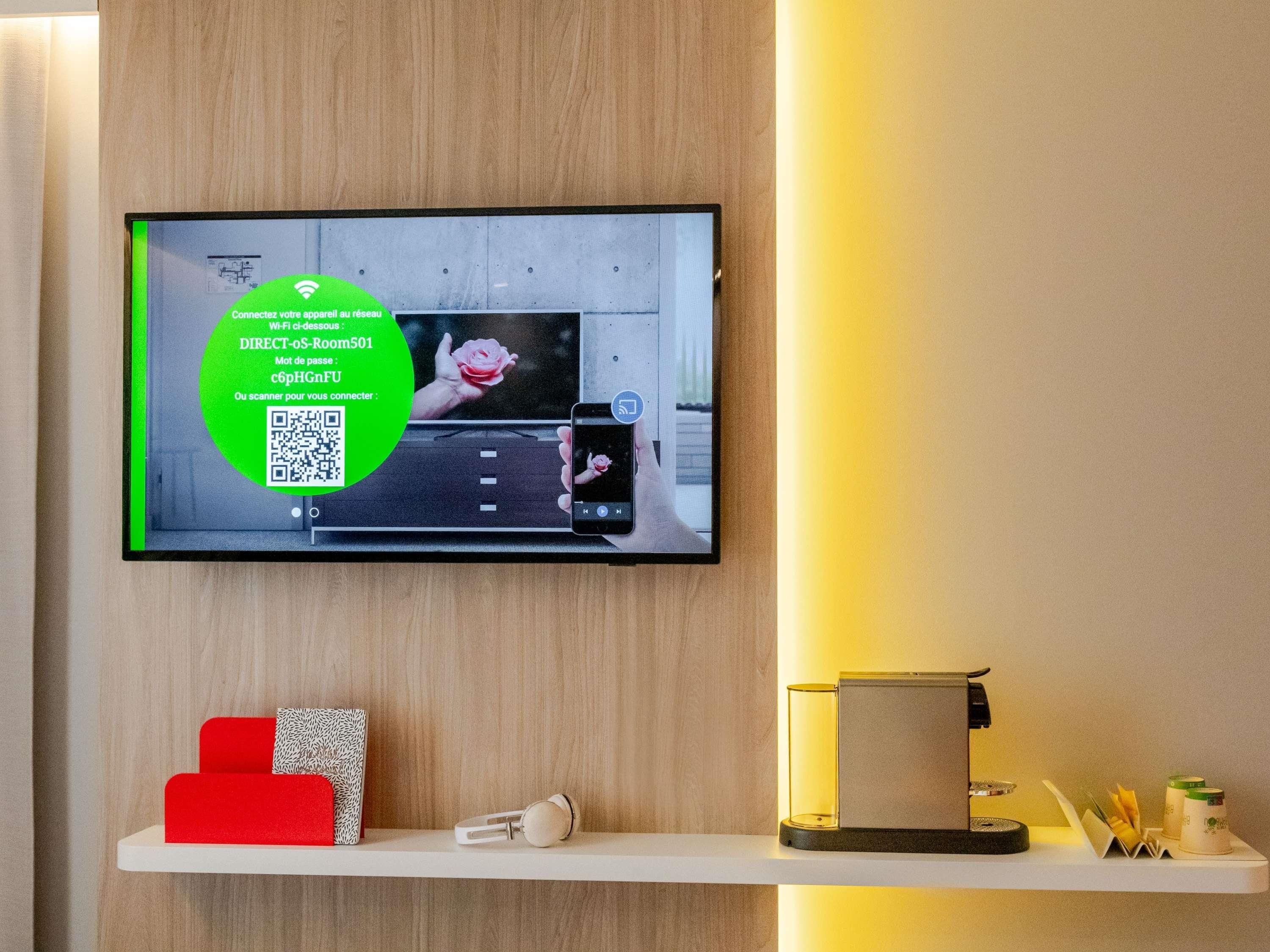 Televisor de pantalla plana montado en una pared de madera que muestra un código QR e instrucciones para Wi-Fi.