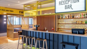Un comptoir d’accueil avec une enseigne, des tabourets de bar, un comptoir et une variété de bouteilles et de verres.