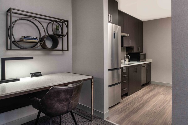A modern kitchen with dark cabinets, stainless steel appliances, and a marble countertop. - Staybridge Suites Boston - Quincy by IHG (Quincy)