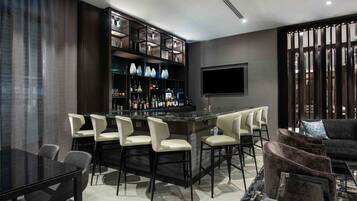A modern bar area with a bar counter, seating, and a TV mounted on the wall.
