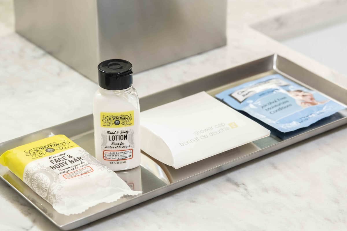 A tray with a cleansing face and body bar, a lotion bottle, and a shower cap.