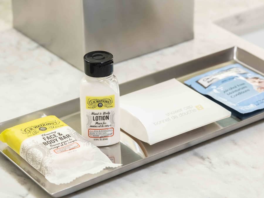 A tray with a cleansing face and body bar, a lotion bottle, and a shower cap.