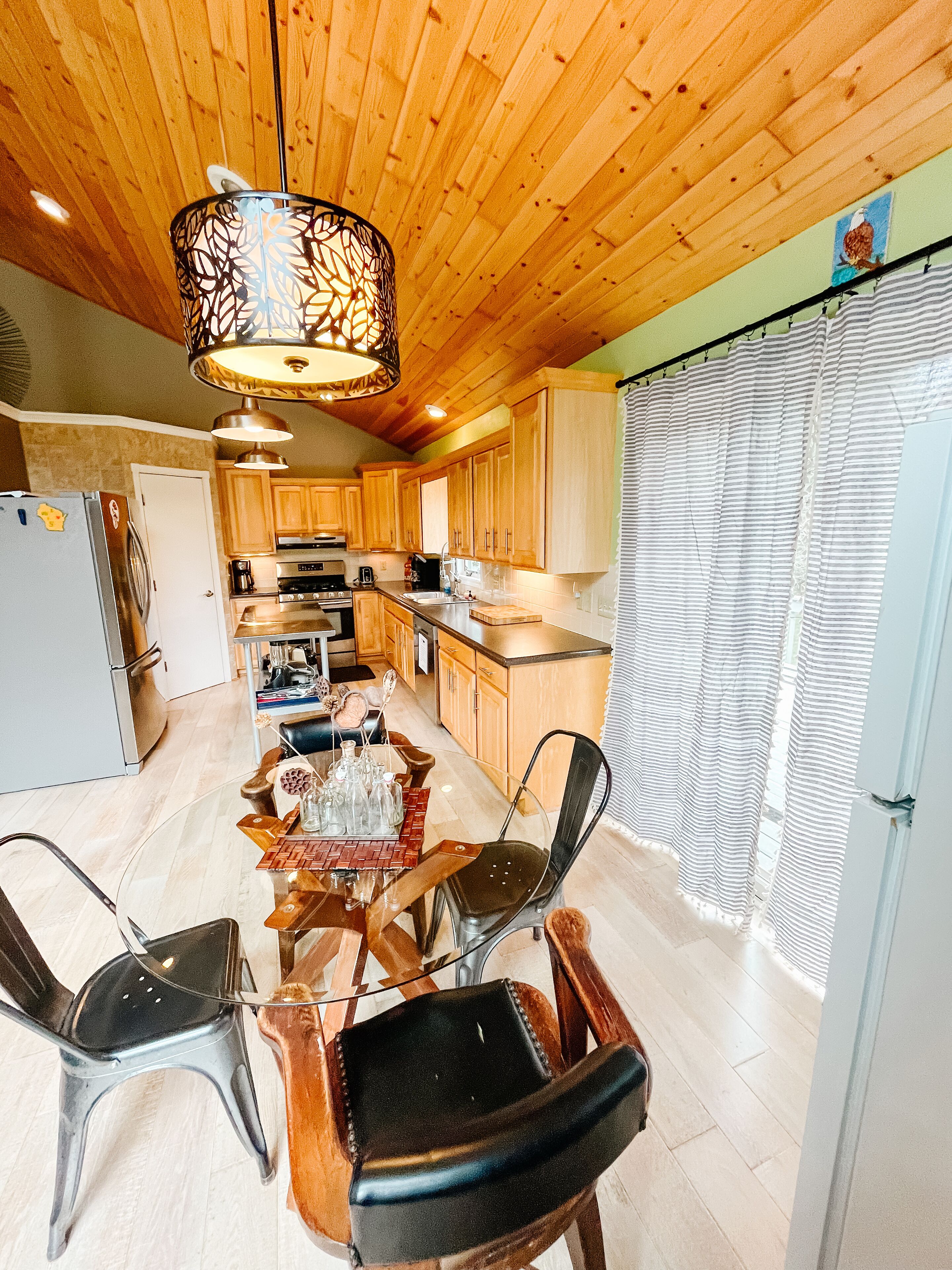 A spacious kitchen with wooden cabinets, a dining area with a glass table, and a modern chandelier.