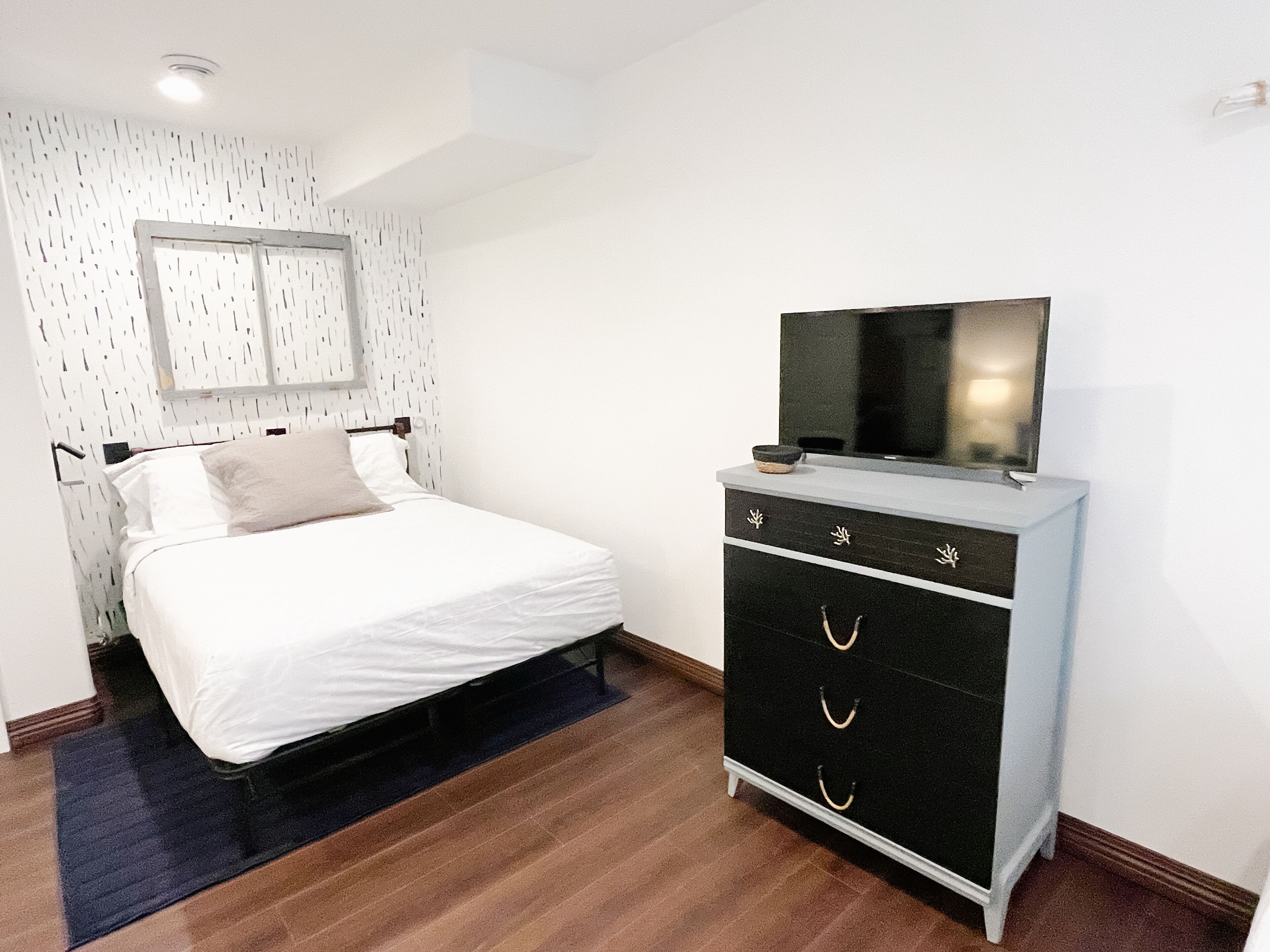 A bedroom with a bed, a dresser, and a television.