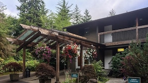A guest check-in area with a wooden pergola, potted plants, and a 'No Vacancy' sign. - Olympic Suites Inn (Forks)