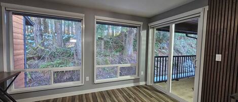 A room with large windows offering a view of a forested area.