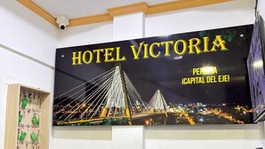 Un mostrador de recepción de hotel con un cartel que dice "HOTEL VICTORIA" y una vista nocturna de un puente.