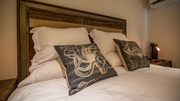 A bed with white linens and two decorative pillows with an octopus design. - Great Rental for Families and Small Groups in Downtown Cabo San Lucas (Cabo San Lucas)
